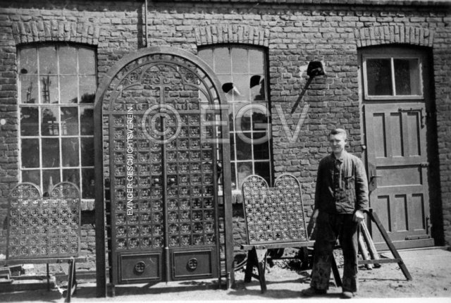 Schmiedemeister Finger vor seiner Schmiede mit einem von ihm gefertigten Tor. Um 1930